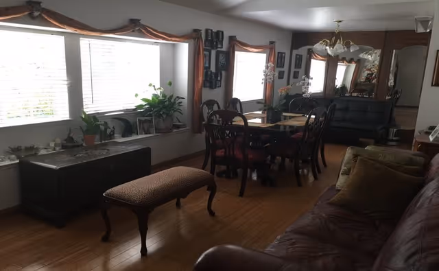 Cozy dining and living space with a wooden table, chairs, and potted plants.