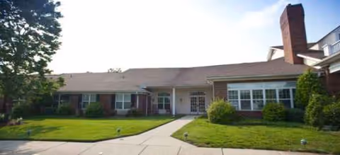 Single-story brick senior living facility with central entrance and manicured front lawn.