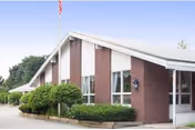 Crestwood Center exterior: brick building with white sloped roof, windows, flag, and landscaped entrance.