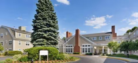 Exterior view of Brookdale Cushing Park with a tall tree and building entrance.