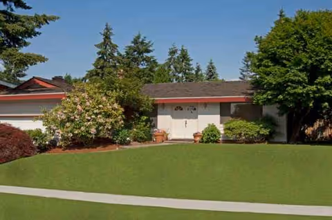 Front view of Evergreen Elderly Care Inc building with green lawn and trees.