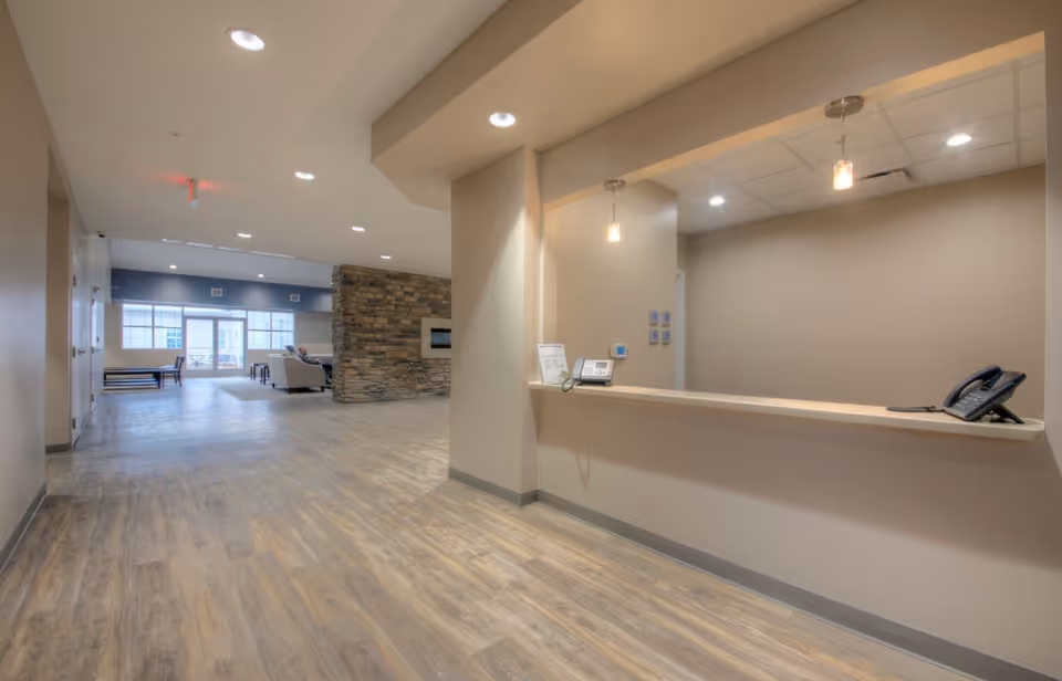 Lobby and reception desk area with a counter and pendant lights, stone accent wall, and seating visible in the distance.