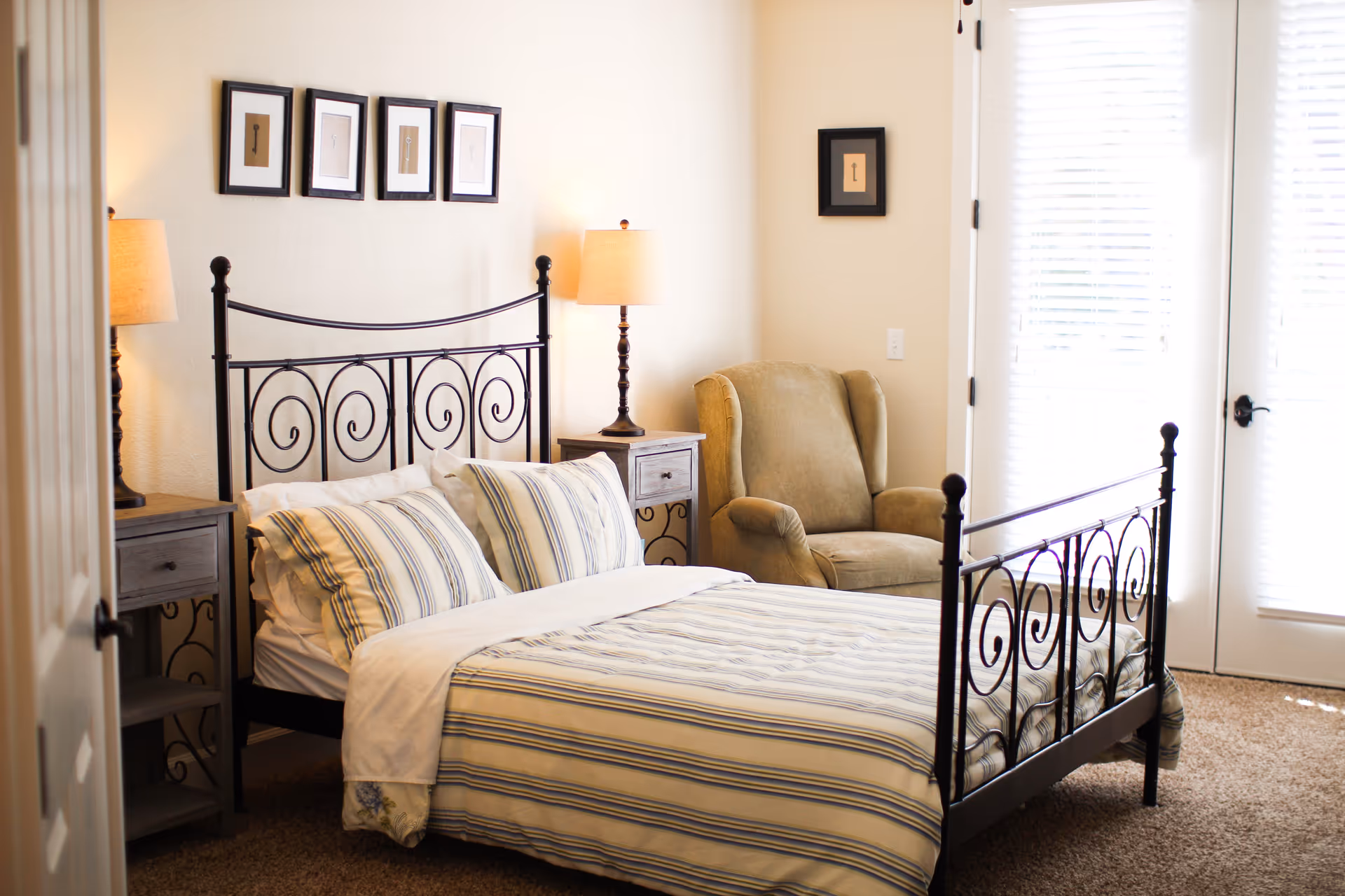 A cozy senior living bedroom with a metal-framed bed, nightstands, and a beige armchair.