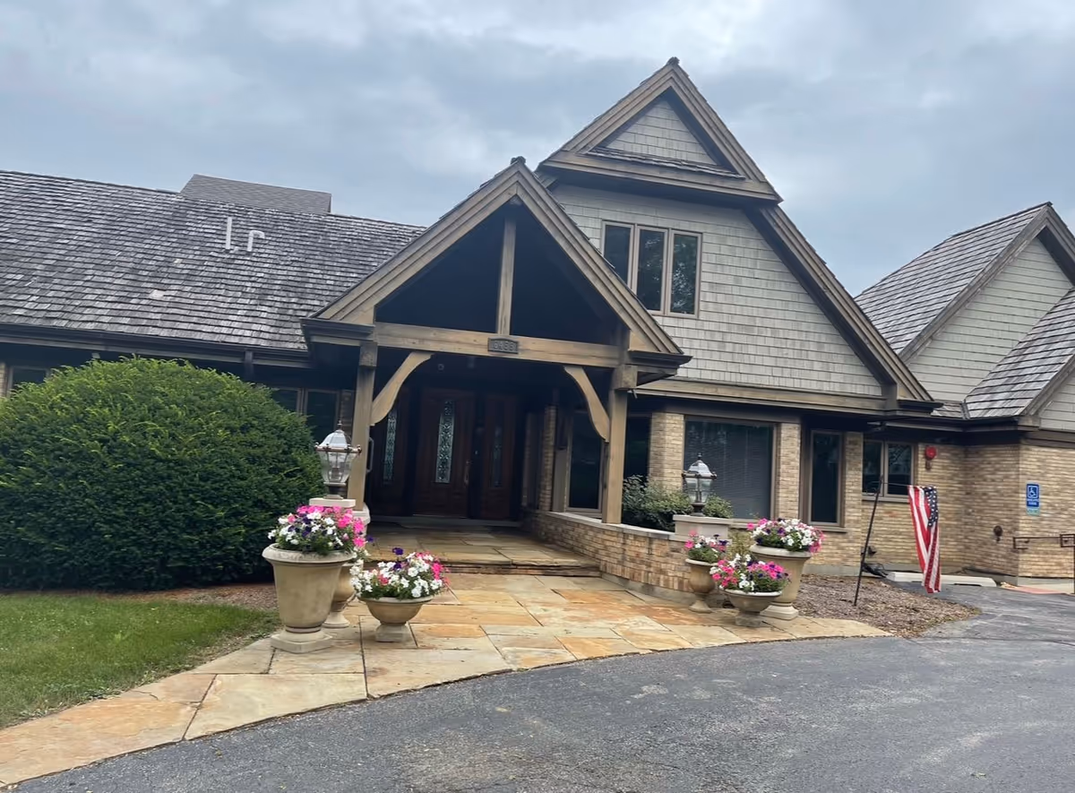 Stone-clad senior living facility entrance with potted flowers.