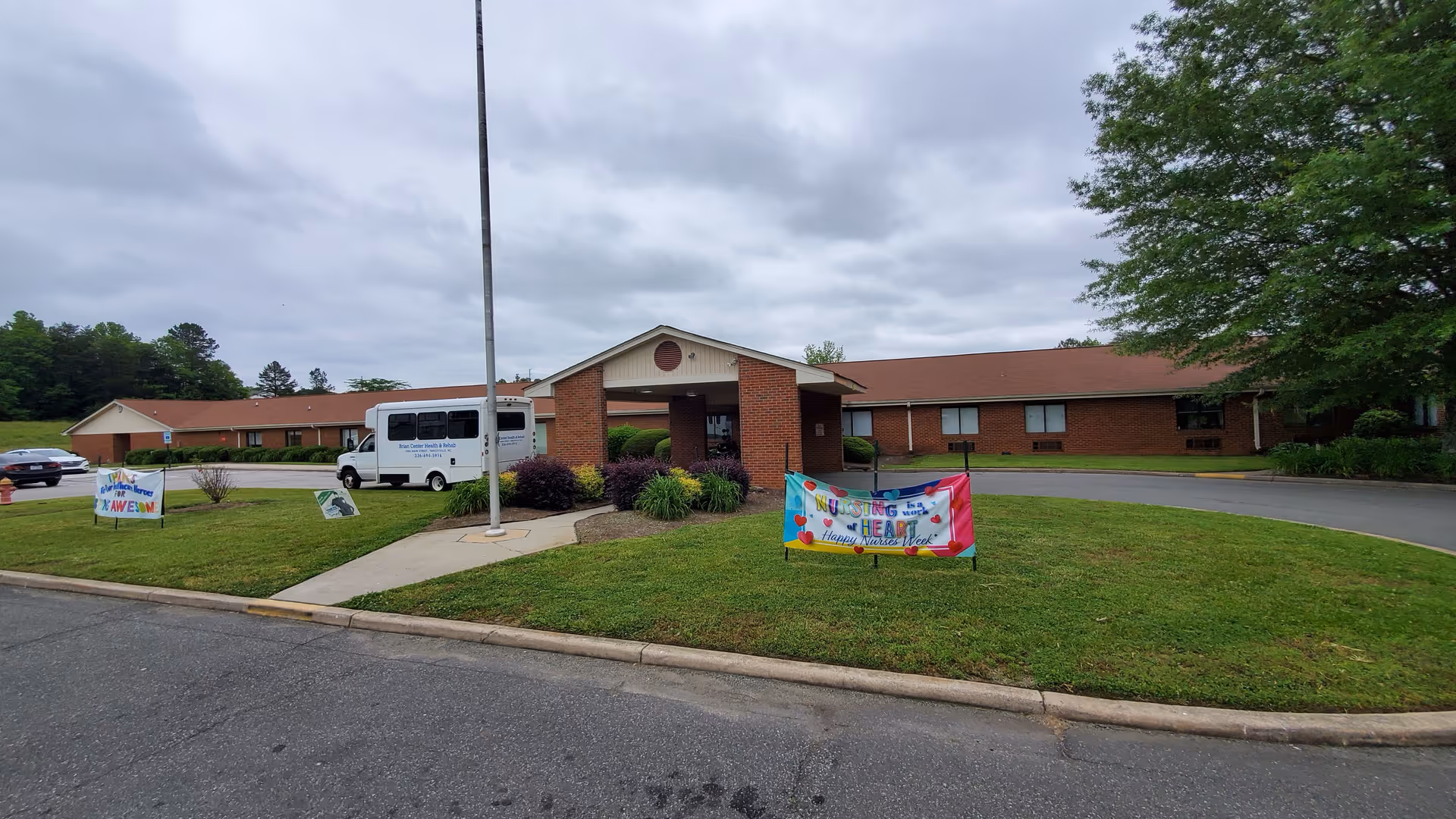 Exterior view of a brick senior care facility with a bus near the entrance.