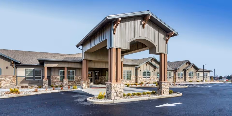 Entrance of a single-story senior living facility with a covered porte-cochere and stone accents.