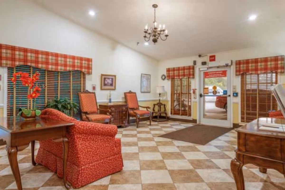 Interior common lounge with red plaid drapes, checkered floor, and seating near glass doors.