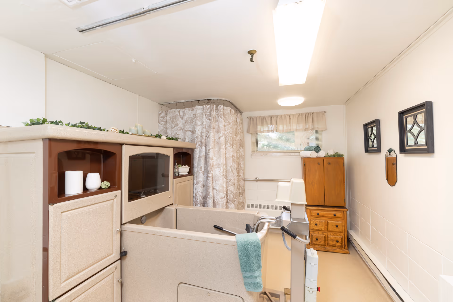 Interior view of a senior living facility bathroom featuring a walk-in tub and wooden storage.