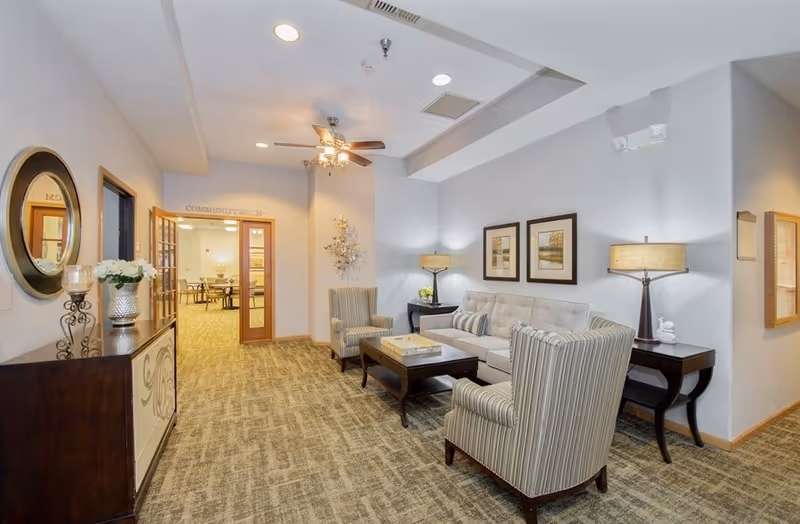 Bright community lounge with a sofa, striped armchairs, coffee table and decorative lamps.