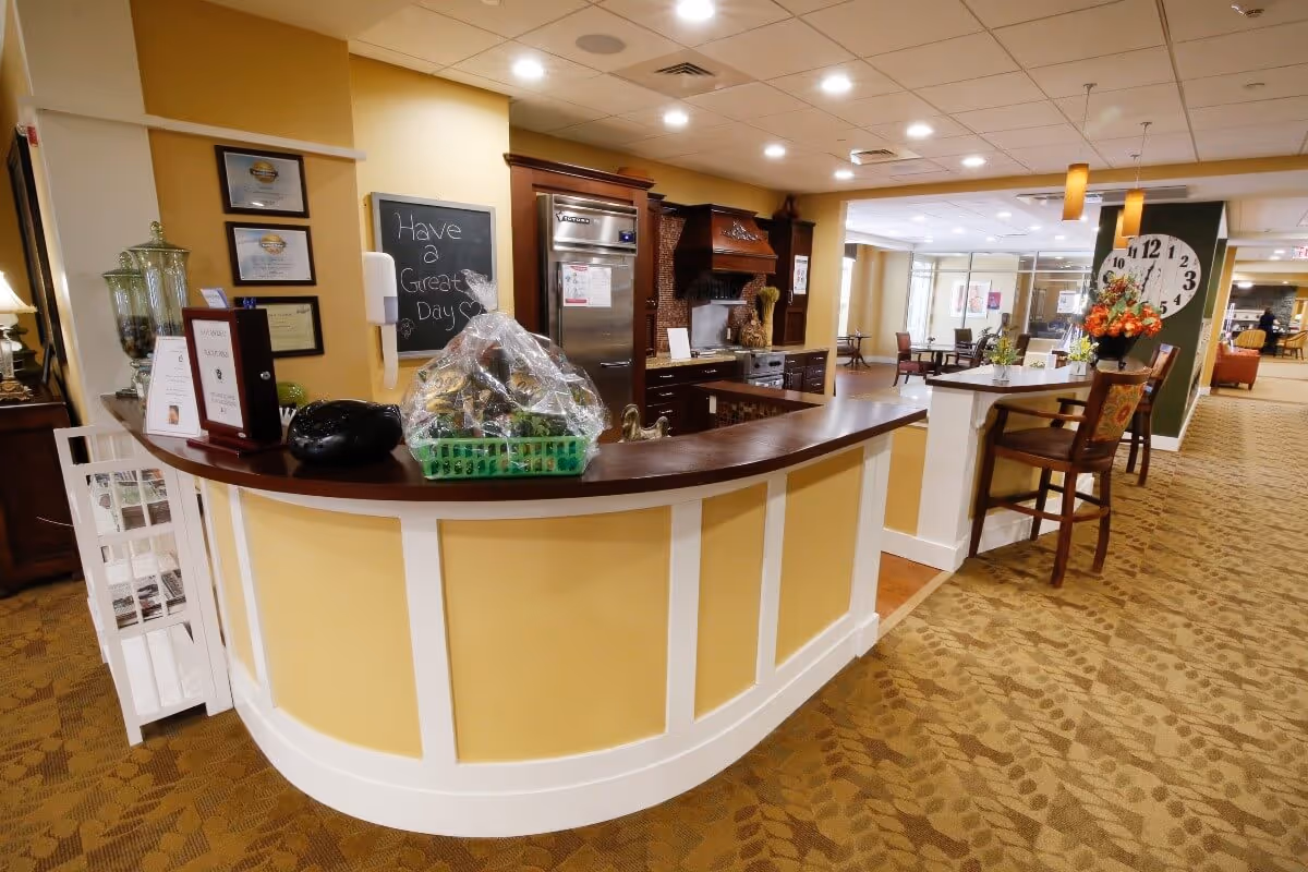 Curved service counter and seating area in a well-lit communal dining/lounge space of a senior living facility.
