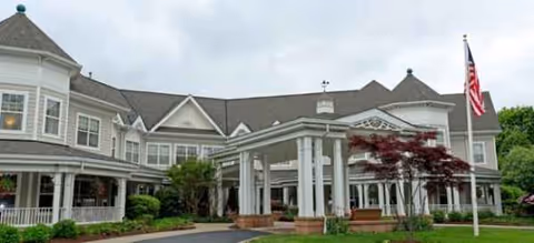 Brookdale Wilton exterior building with white pillars, entrance, and flag on a curved driveway.