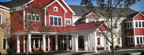 Exterior view of Eastview at Middlebury with colorful red and beige buildings and a covered entrance.