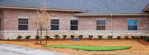 Exterior view of Remarkable Healthcare of Seguin with shrubs, a tree, and a paved area.