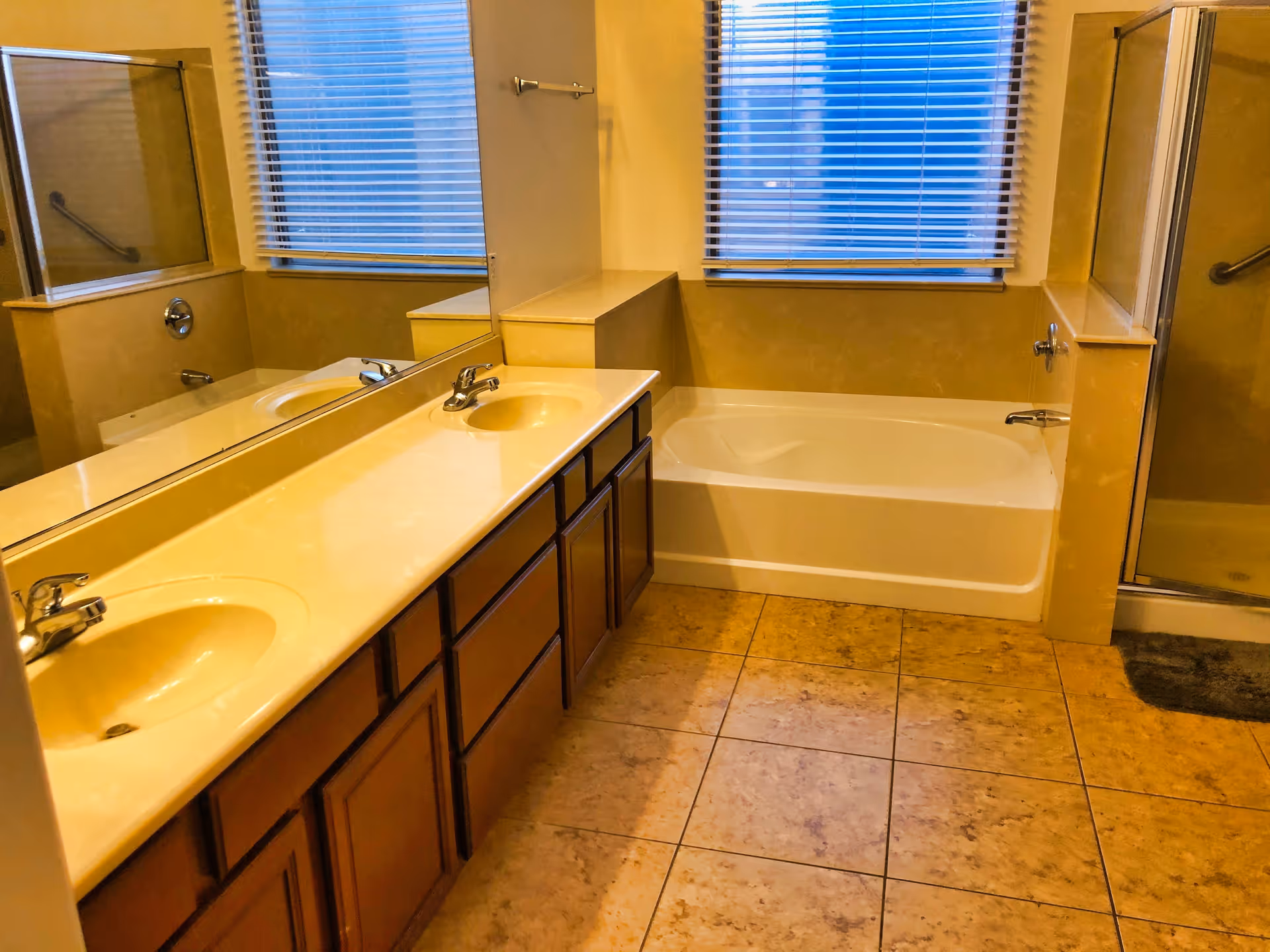 Spacious bathroom with a double-sink vanity and large mirror, a bathtub under a window, and a separate glass shower.