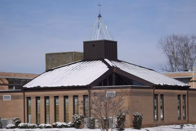 Snow-covered brick facility exterior with a slanted roof at Woodbridge of Clinton.