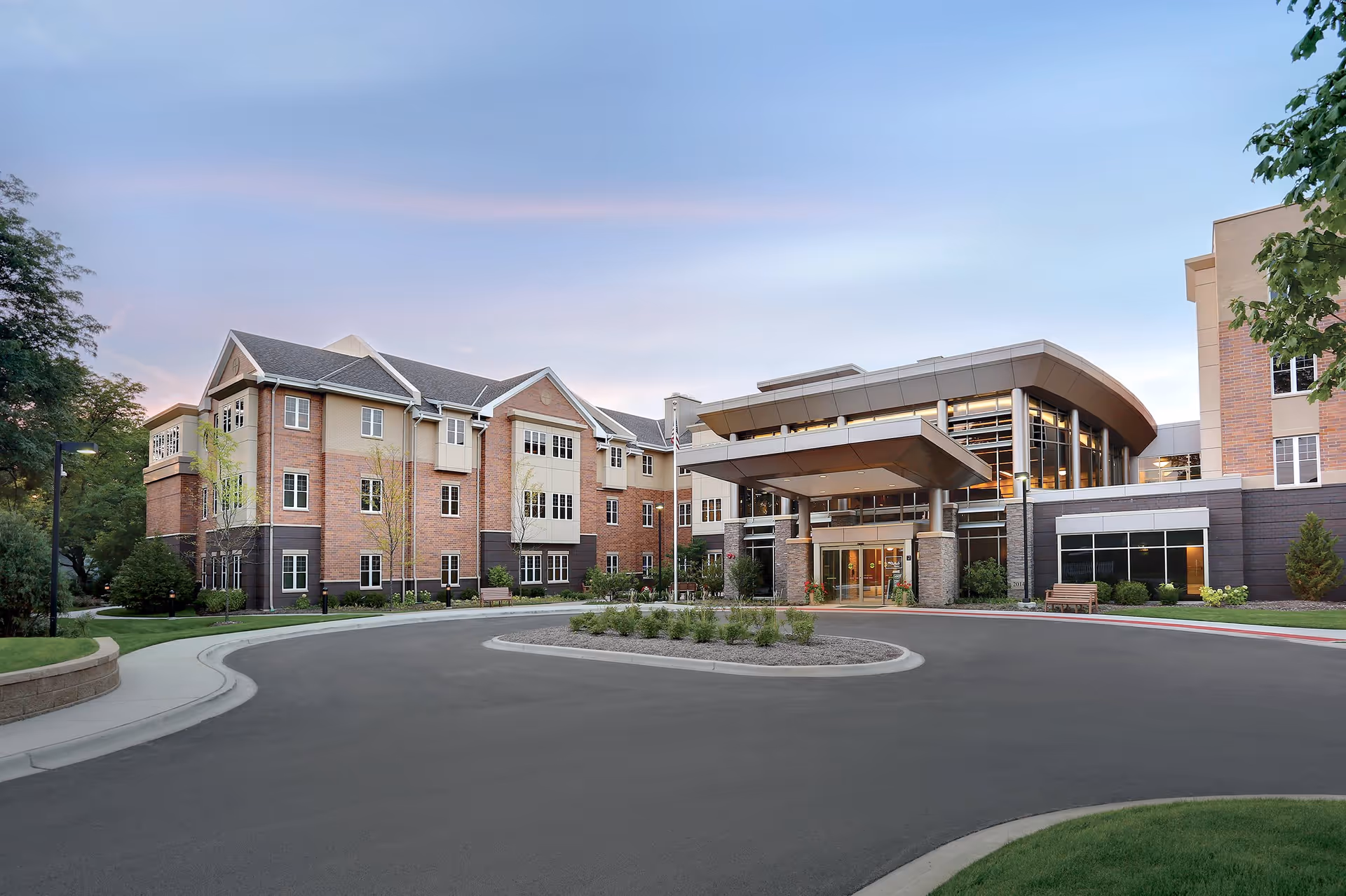 Front entrance of Hearthstone of Arlington Heights, a multi-story brick senior living building with a covered porte-cochère and circular driveway.