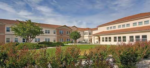 Exterior view of Magnolia Court senior living campus with green lawn and shrubs.