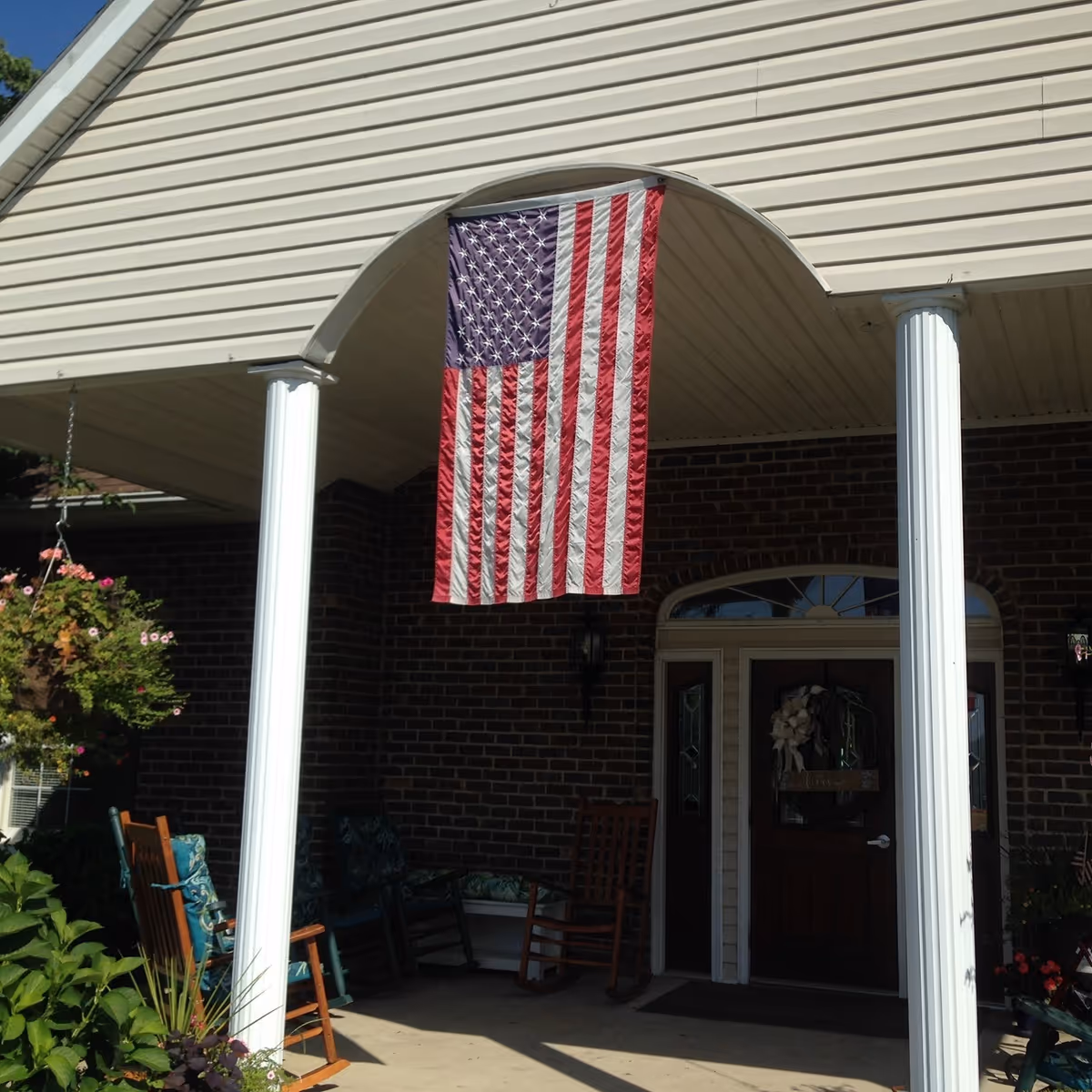 American flag hangs on the front porch of a brick senior living building.