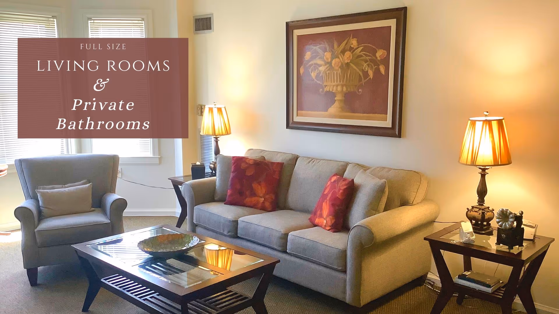 Living room with a beige sofa and armchair, glass-top coffee table, side tables with lamps, and framed wall art.