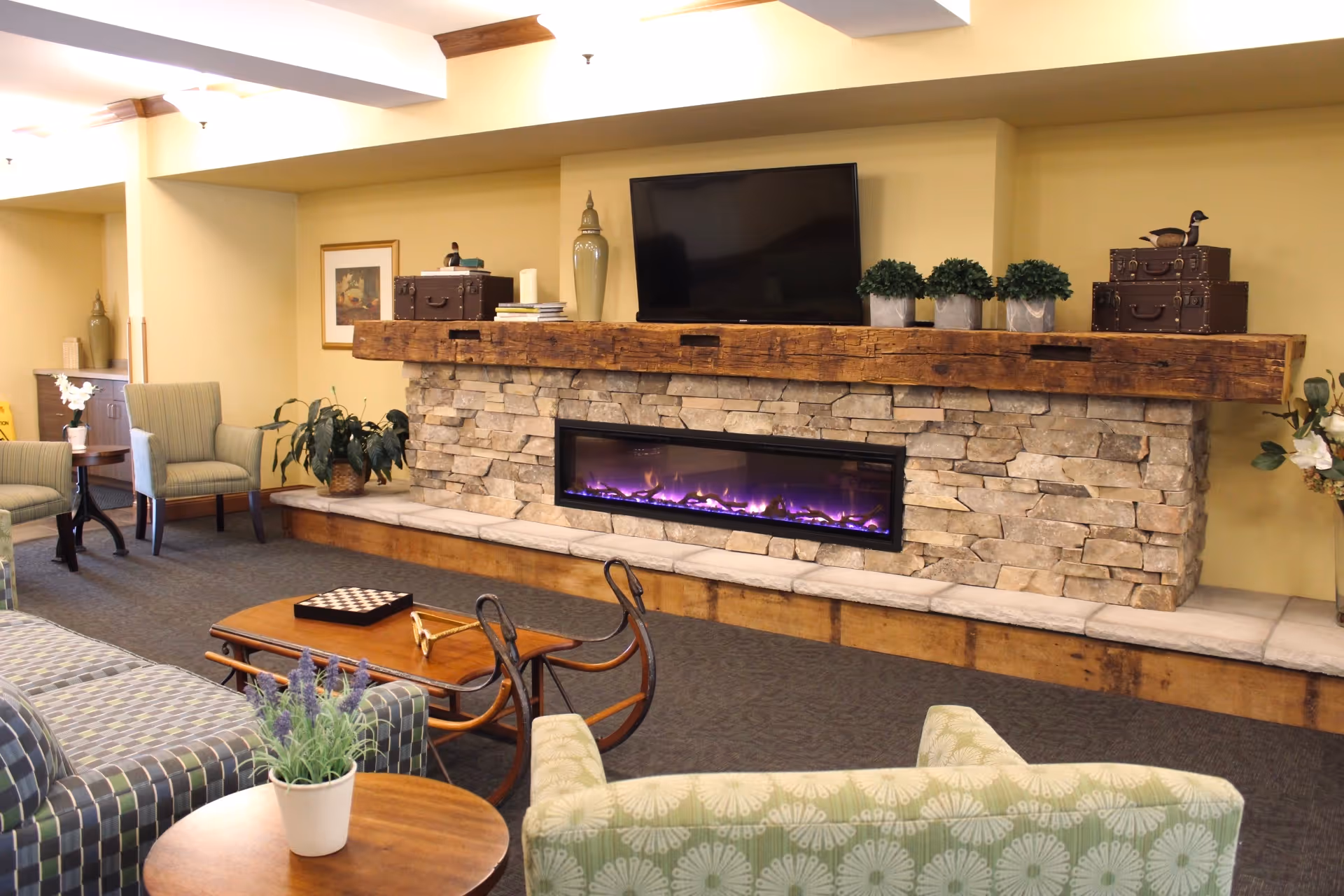 Cozy lounge area with a stone fireplace, wall-mounted TV, seating and coffee tables.