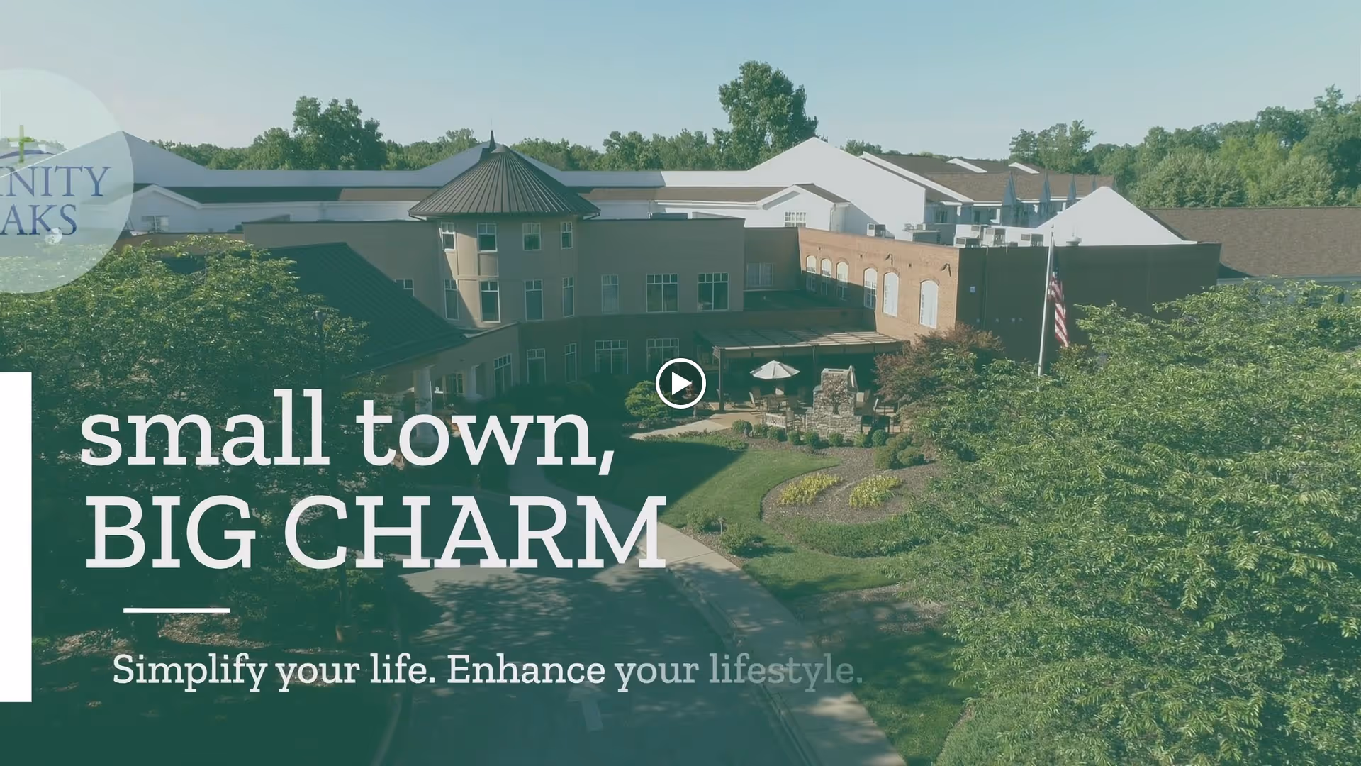 Aerial view of the Trinity Oaks senior living facility showing a large building surrounded by trees and landscaped gardens under a clear sky.