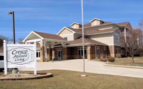 Exterior view of an assisted living facility with a front entrance and sign.