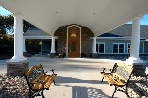 Covered entrance with stone facade and two wooden benches.