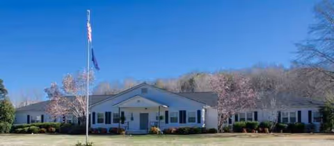A single-story facility with a front entrance, flagpole, and landscaped lawn.