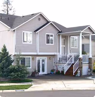 Residential two-story building exterior with stairs to the front entrance and landscaping.