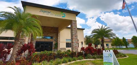 Front exterior view of Inspired Living at Ivy Ridge with palm trees and entryway