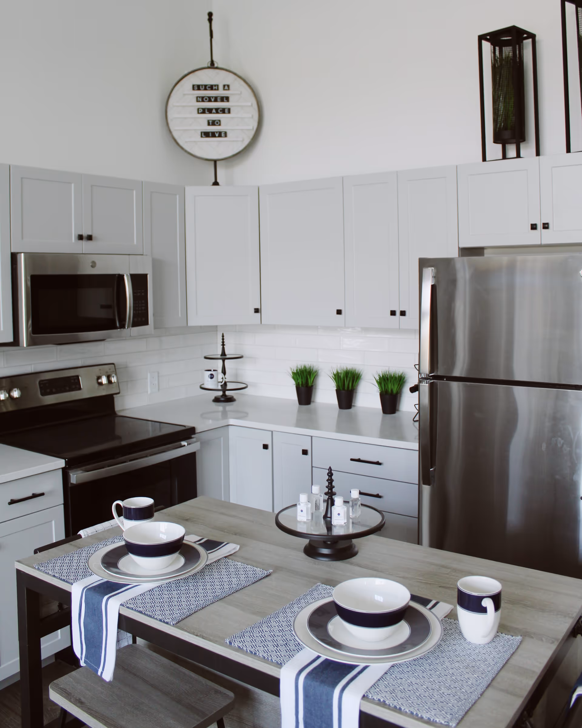 Bright modern kitchen with white cabinets, stainless steel appliances, and a set dining island with place settings.
