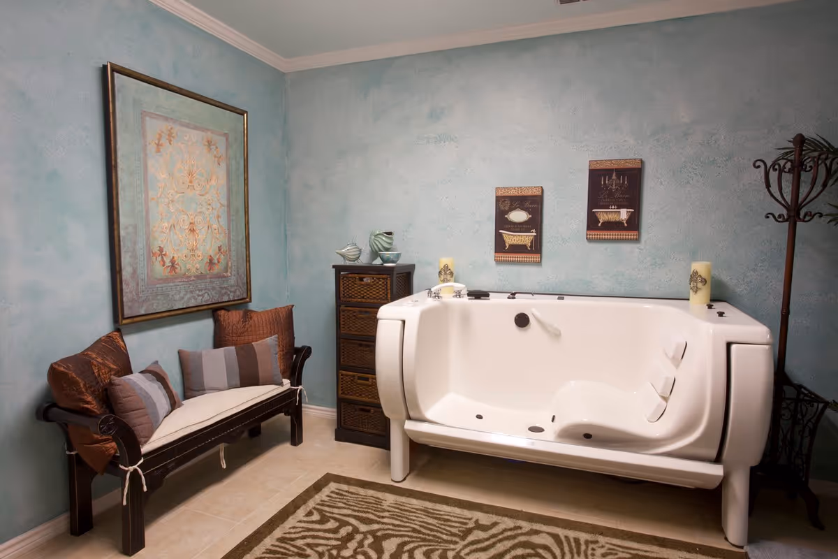 Decorated bathroom with a white walk-in tub, cushioned bench, wicker cabinet and teal textured walls.