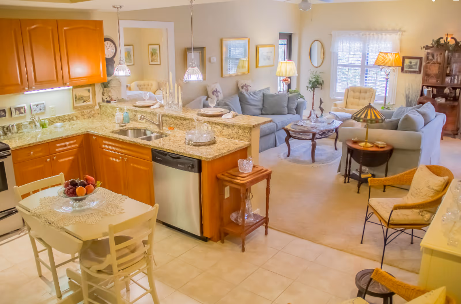Open-plan kitchen and cozy living area with granite countertops, a small dining table, and sofas under warm lighting.