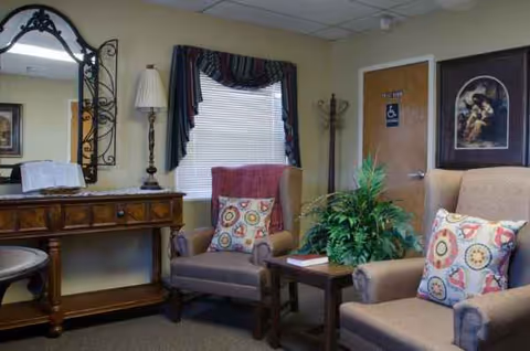 Cozy senior living lounge with armchairs, plants, and a window.