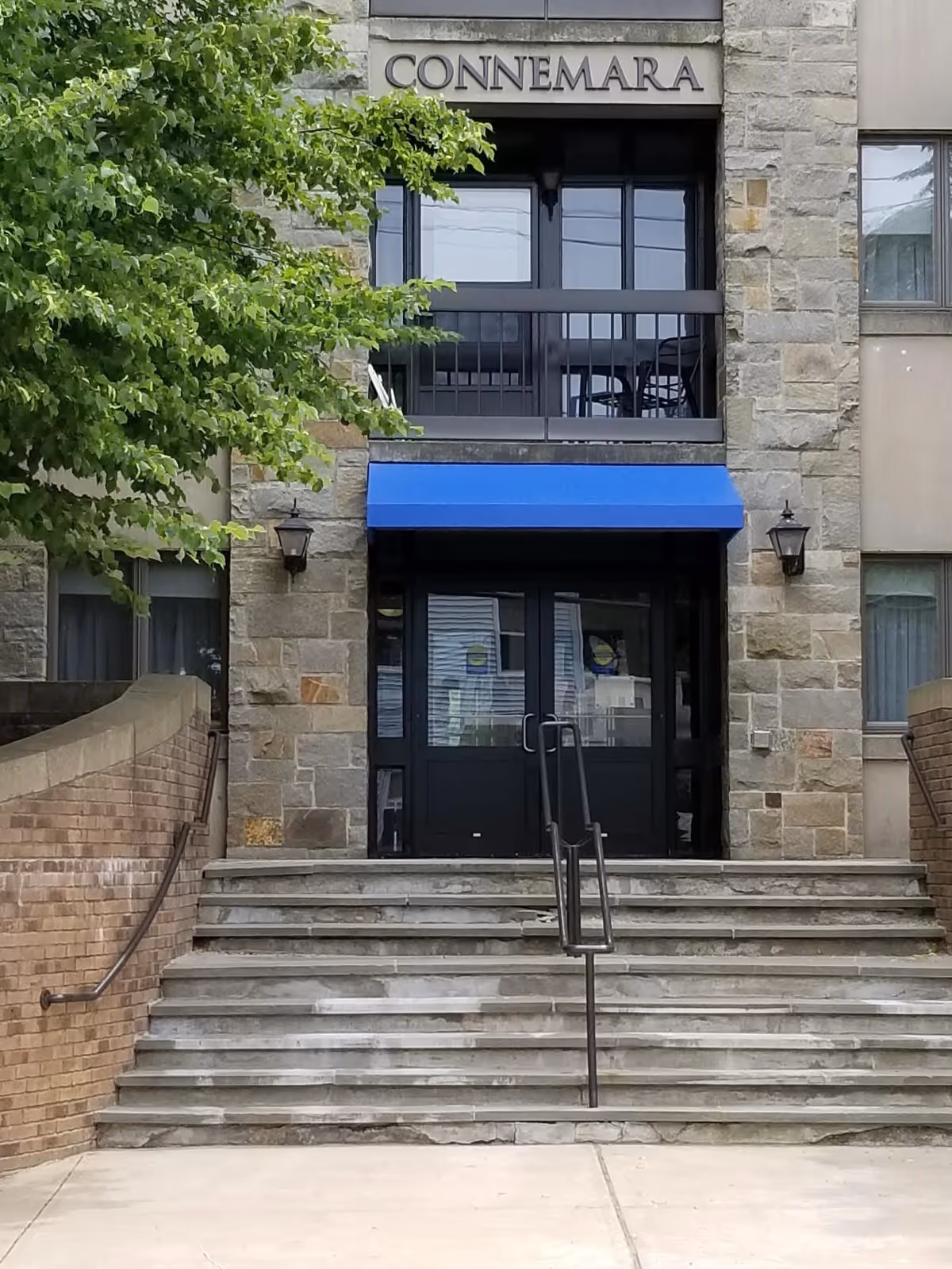 Stone-faced building entrance with steps, a blue awning over double doors and a 'CONNEMARA' sign above.