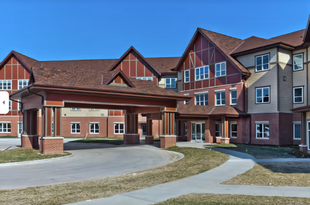 AVIVA Woodlands exterior: brick senior living building with a covered entrance and curved driveway.
