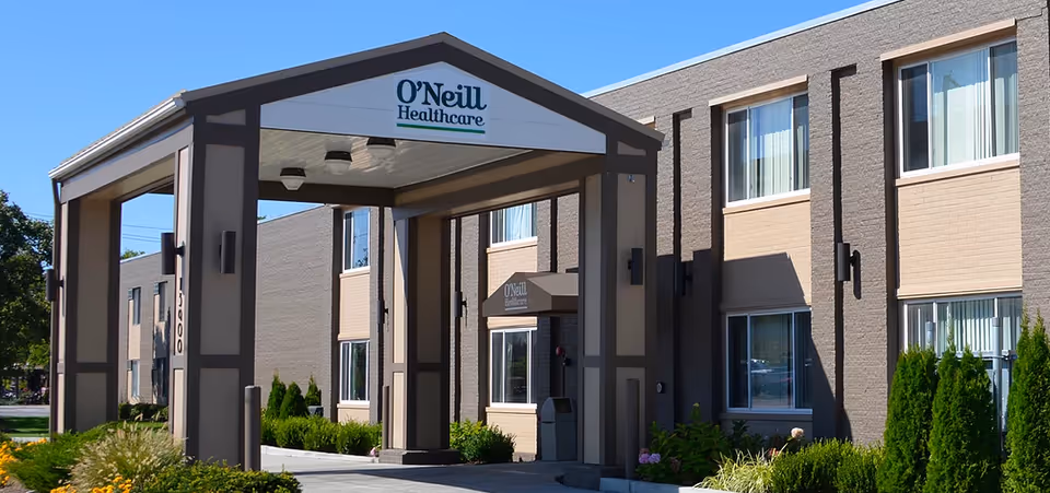 Front entrance of O'Neill Healthcare building with a covered porte-cochère and landscaped shrubs.