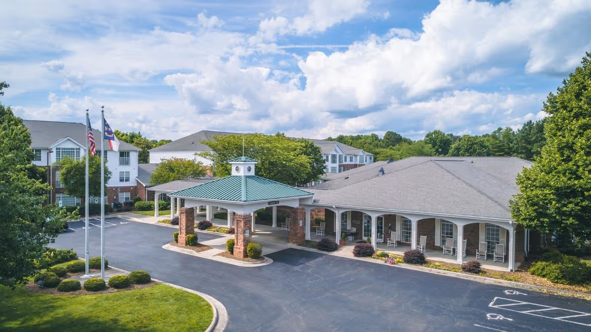 Front entrance of RidgeCrest senior living facility with a covered porte-cochère, flagpoles, and landscaped grounds.