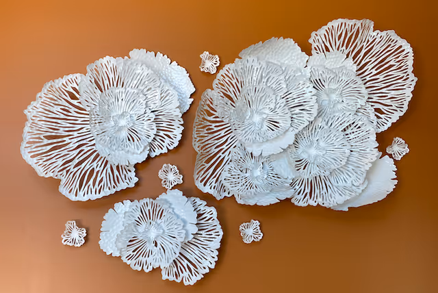 White decorative wall art resembling layered coral or sea anemone shapes mounted on a brown wall.