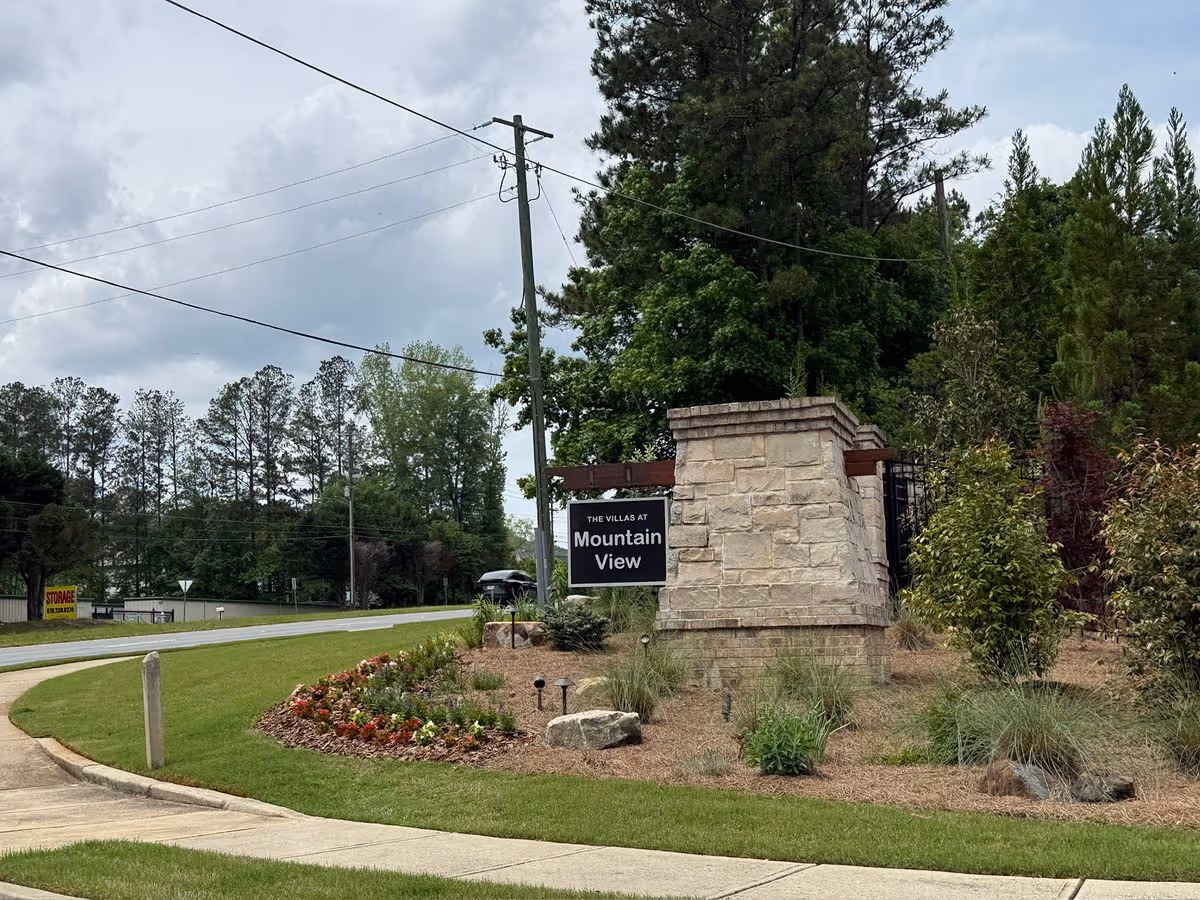 Stone entrance sign reading 'Mountain View' with landscaping and trees beside a roadside.