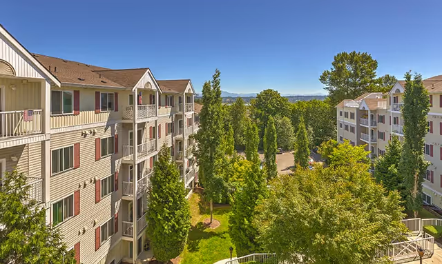Exterior view of Vintage Everett Apartment Homes with balconies, trees, and blue sky.
