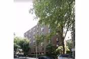 Brick Weinberg Gardens senior living building along a tree-lined street with parked cars.