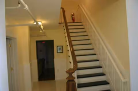 Interior hallway with a wooden banister staircase leading to upper floors.