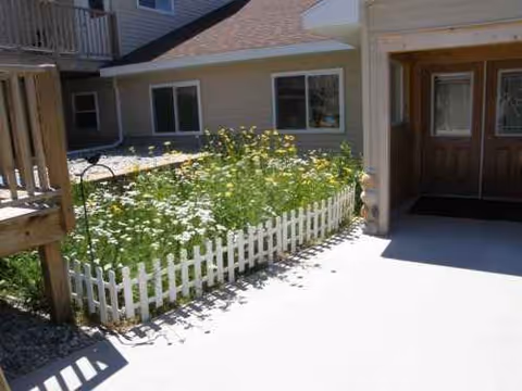 Exterior view of Culver Meadows entrance with a white picket fence and blooming flowers.