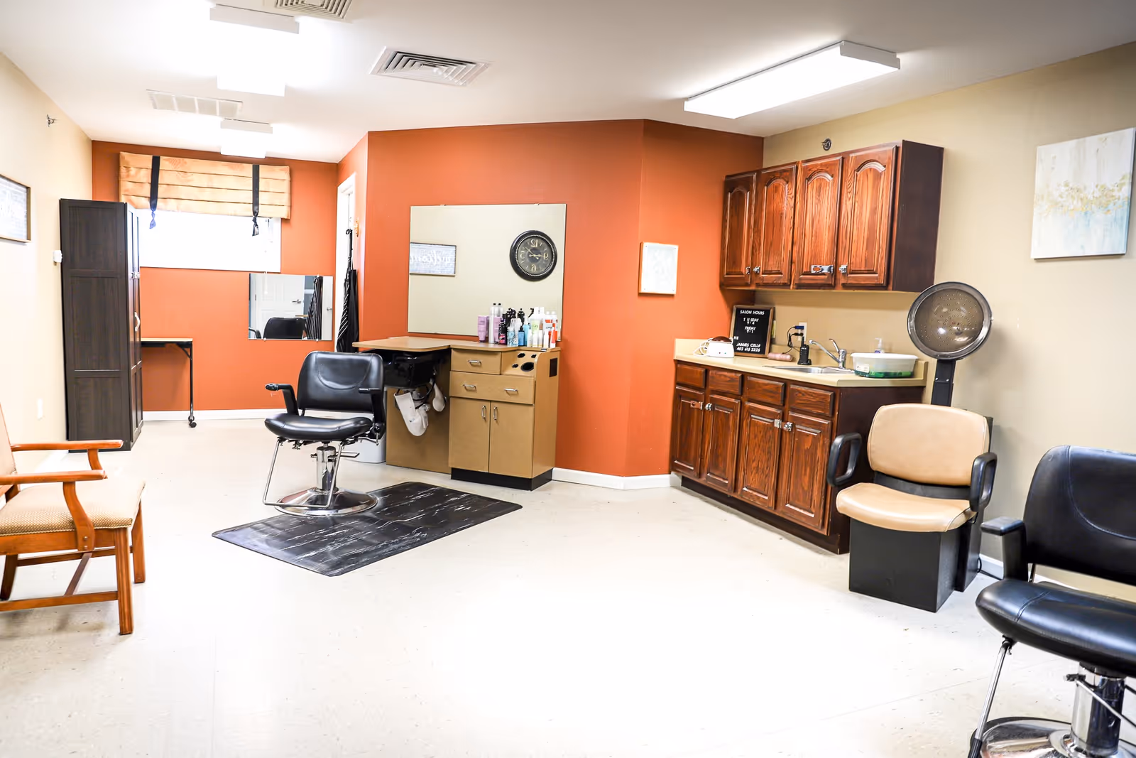 A salon-style interior with styling chairs, a shampoo sink, cabinets, and hair products.