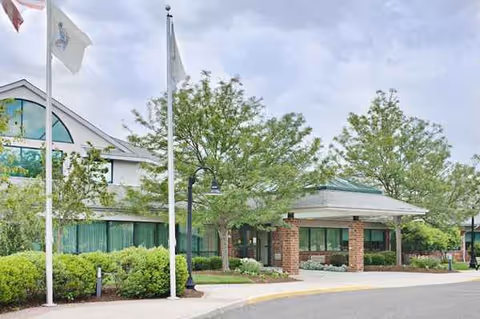 Exterior view of a senior living facility entrance with brick columns and landscaping.