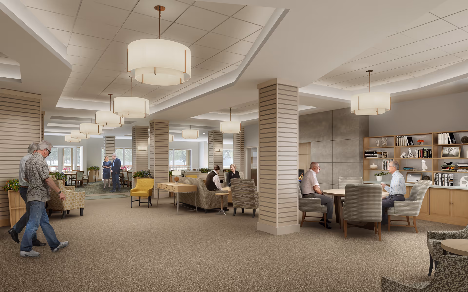 A spacious, well-lit senior living common area with beige carpeting and modern ceiling lights. Several elderly people are seen walking and sitting in groups, engaging in conversation. The room features comfortable chairs, tables, decorative plants, and a bookshelf with various items. Large windows allow natural light to fill the space.