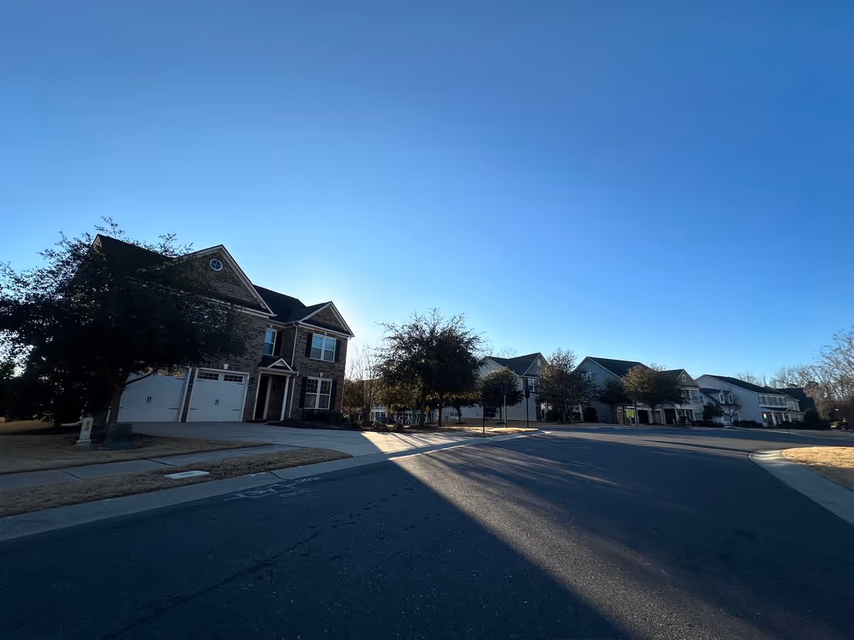 Street view of a suburban cul-de-sac with a row of two-story houses and a clear blue sky.