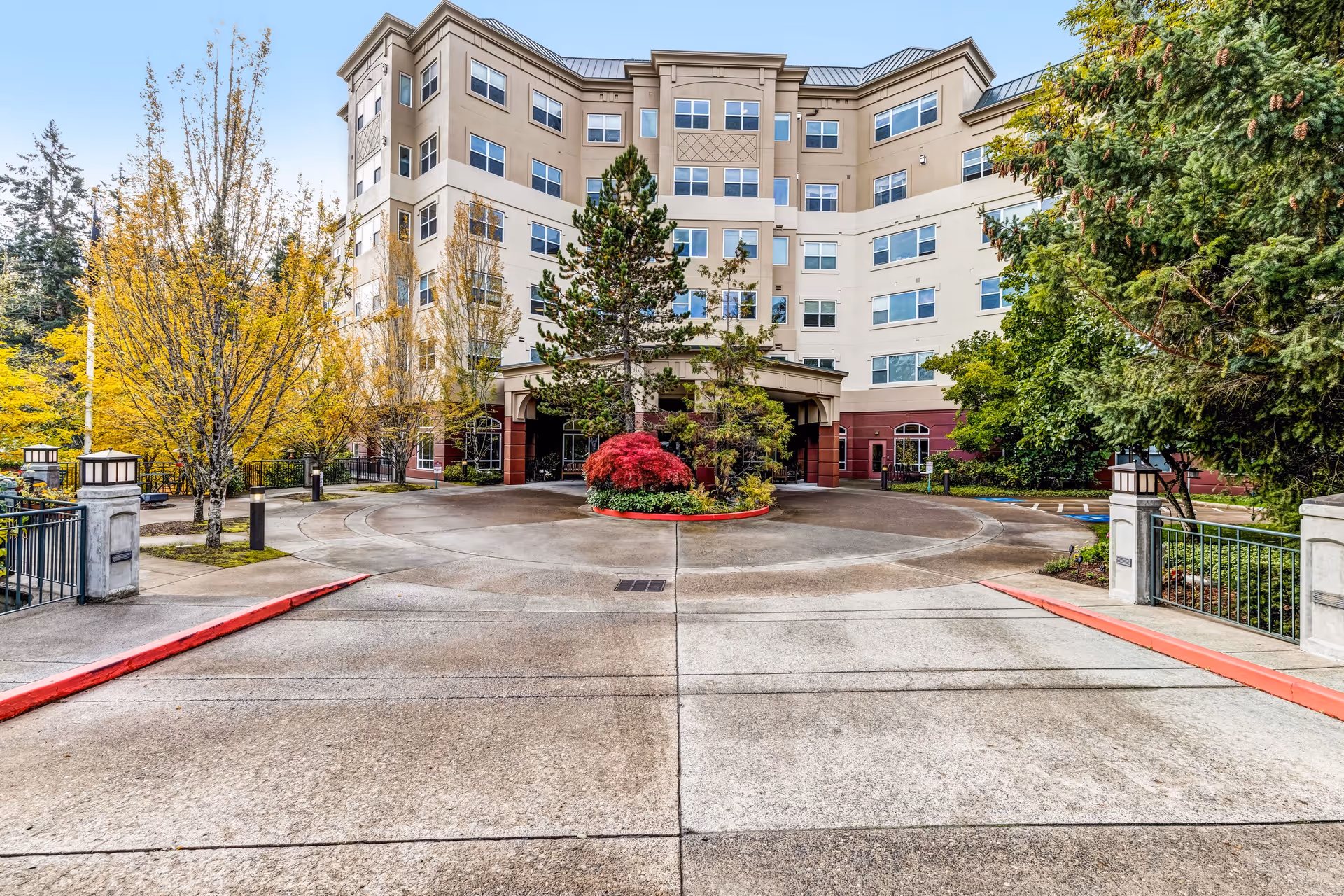 Front exterior view of a multi-story senior living facility named Miramont Pointe, featuring a circular driveway with landscaped greenery and trees around the entrance.