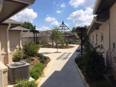 Outdoor courtyard at Sherwood Health Care Facility with walkway, trees, and central gazebo.